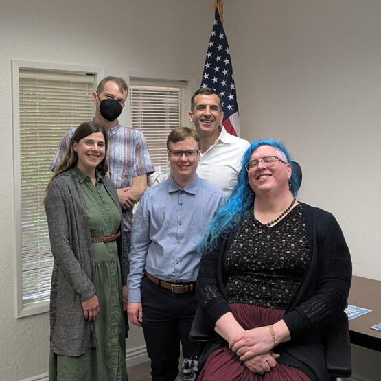 Five people in front of an American flag smiling at the camera